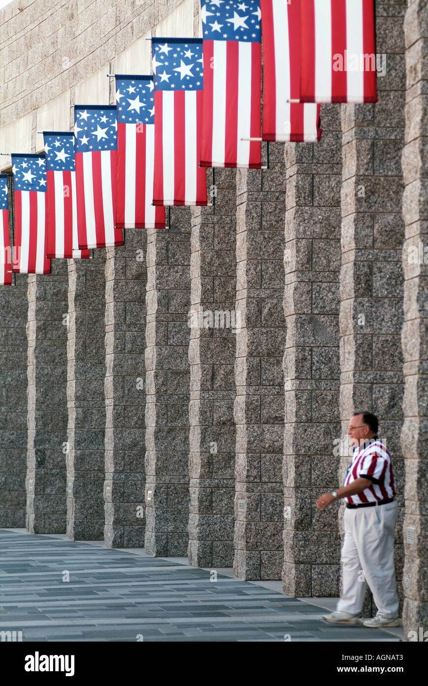 Tourist in American Flag shirt walking under American Flags at Mount Rushmore National Memorial National Park Service Stock Photo