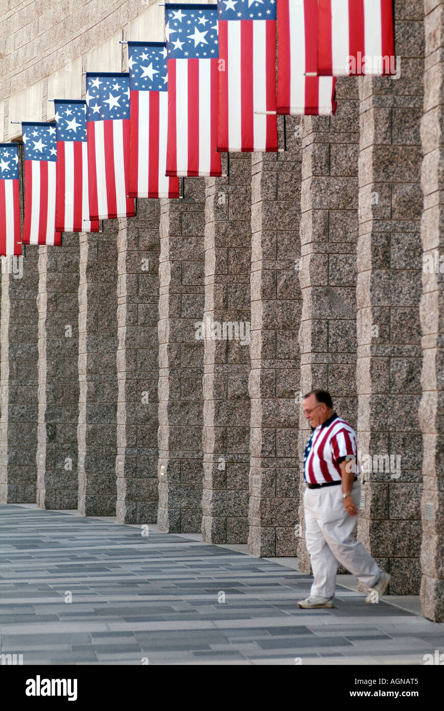 Tourist in American Flag shirt walking under American Flags at Mount Rushmore National Memorial National Park Service Stock Photo