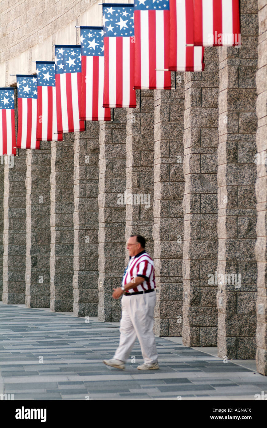 Tourist in American Flag shirt walking under American Flags at Mount Rushmore National Memorial National Park Service Stock Photo