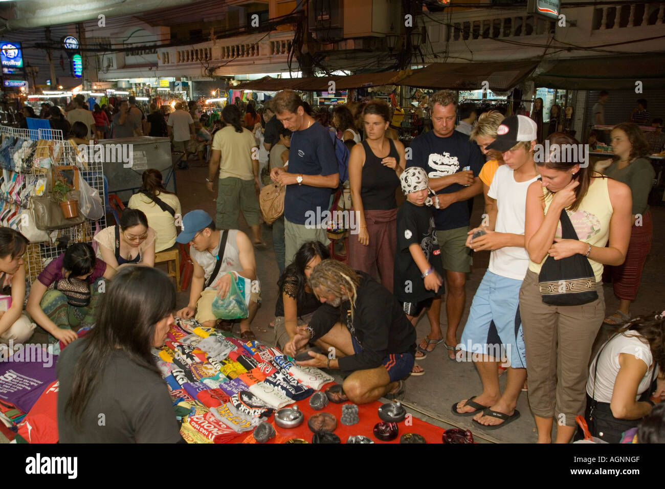 Tourists shopping at Th Khao San Road in the evening Banglamphu Bangkok Thailand Stock Photo