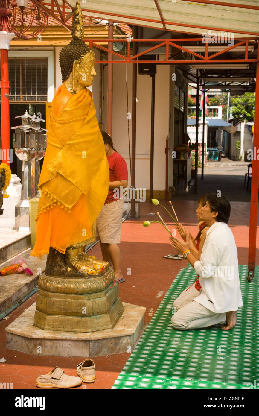 Women praying in front of gilded Buddha statue Wat Intharawihan Banglamphu Bangkok Thailand Stock Photo