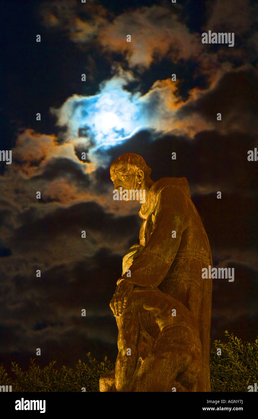 Mexico, San Miguel de Allende, The Jardin, Statue of Fray Juan de San Miguel at night under the moon and clouds. Stock Photo