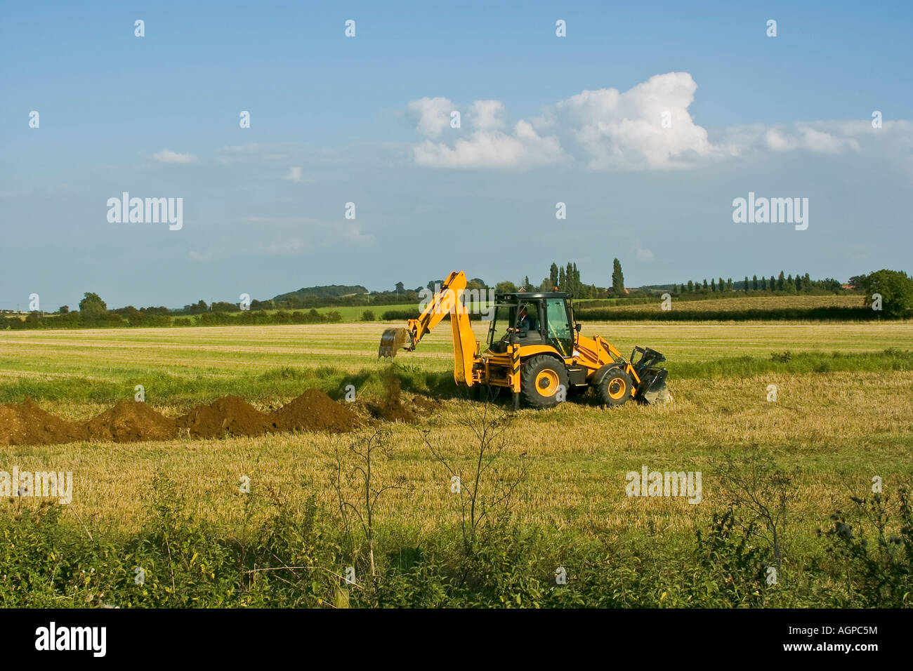digger in countryside digging holes in the ground Stock Photo Alamy