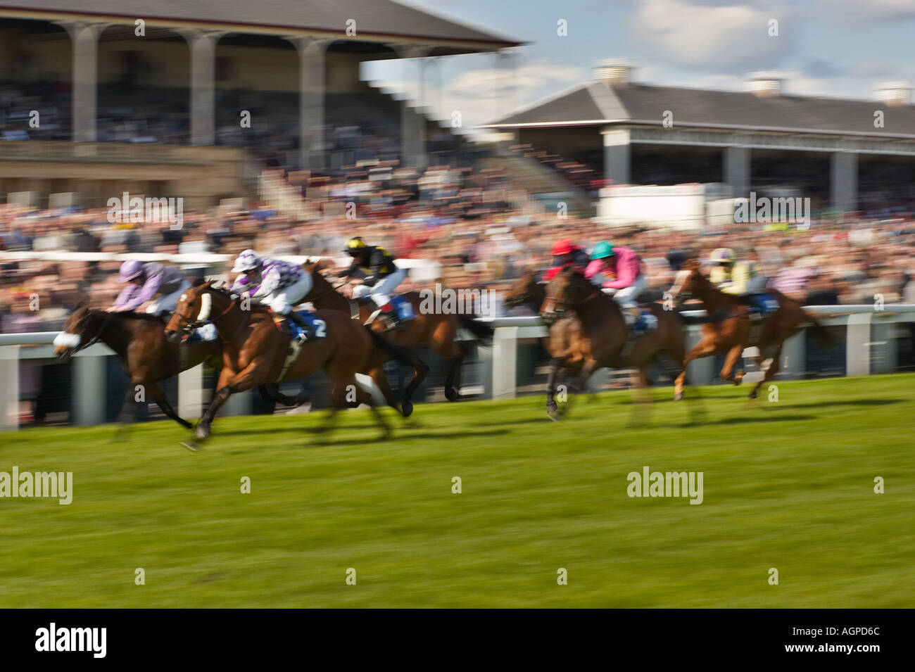 Blurred horses in horse racing in front of a large crowd Stock Photo