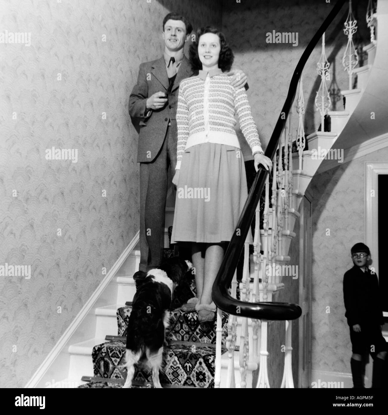 OLD VINTAGE BLACK AND WHITE FAMILY SNAPSHOT PHOTOGRAPH OF MARRIED COUPLE STANDING ON STAIRCASE IN HOUSE CIRCA 1950 Stock Photo