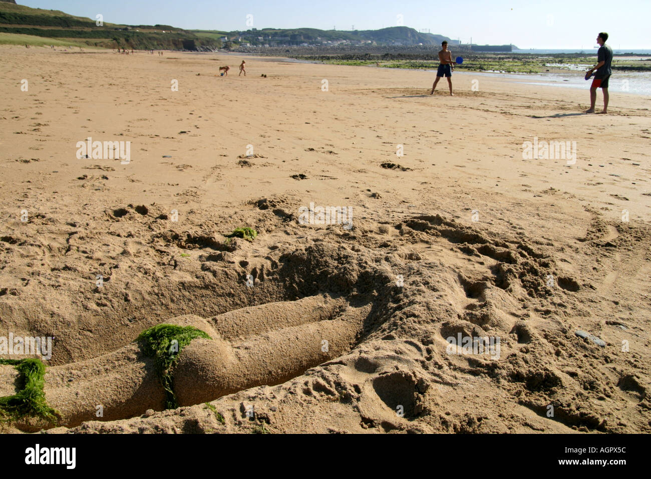 sand sculpture of womans torso sunbathing on beach in Normandy France