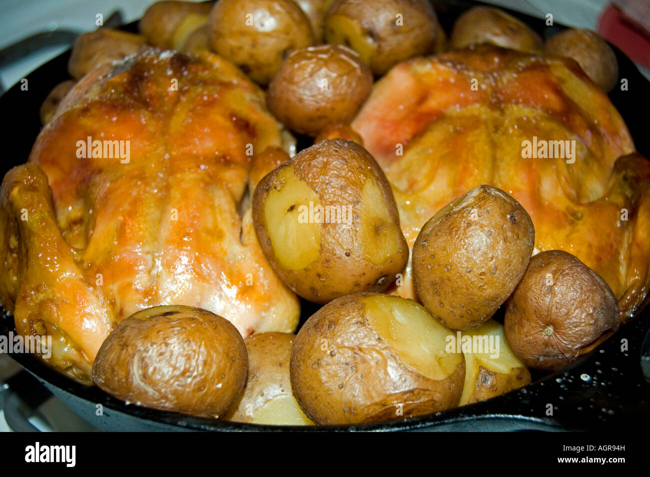 Cornish game hen and potatoes in an iron skilled Stock Photo
