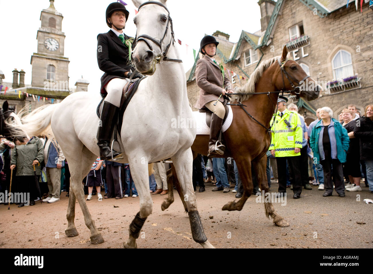 Traditional Scottish event Langholm Common Riding horses coming out of Kirk Wynd into Langholm town centre with town hall behind Stock Photo