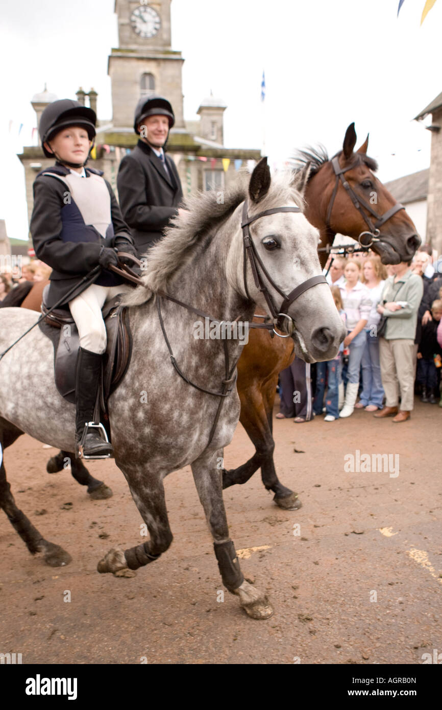 Traditional Scottish event Langholm Common Riding horses coming out of Kirk Wynd into Langholm town centre with town hall behind Stock Photo