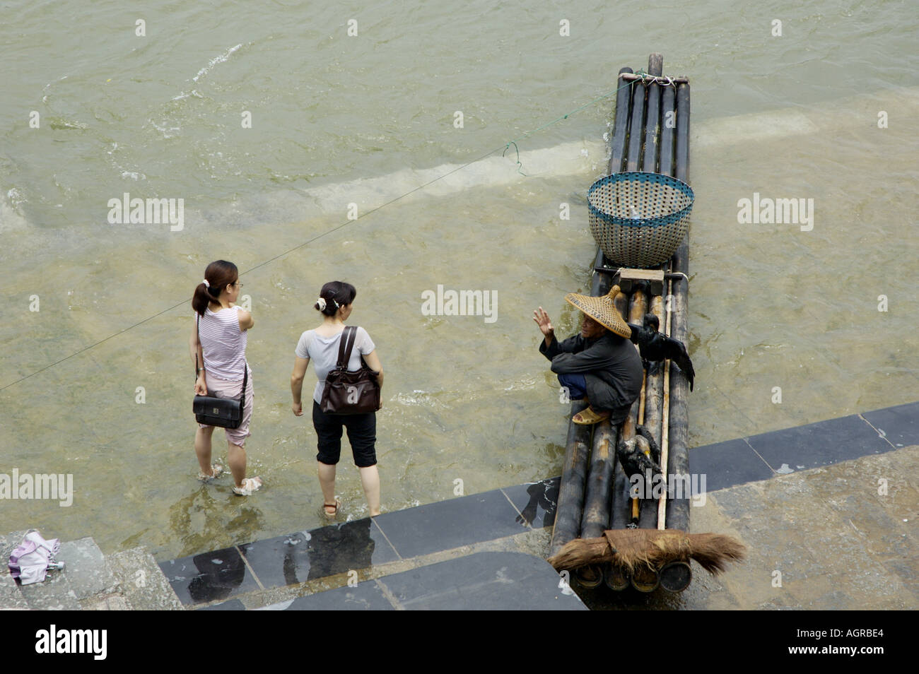 China Guangxi Yangshuo Two Women Visiting The Village And Talking To A Cormorant Fisherman On Li River Stock Photo