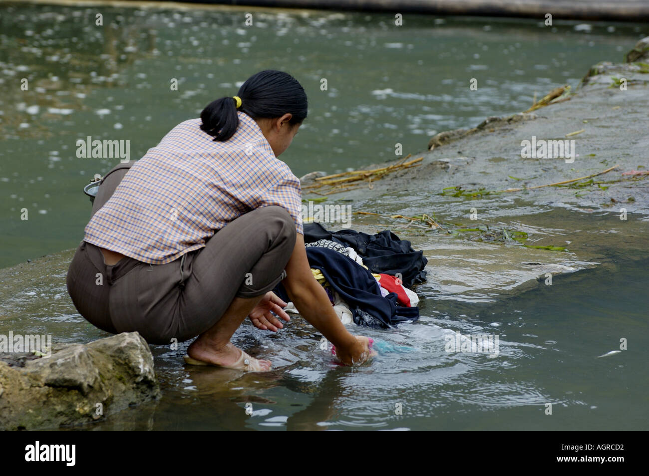 Woman washing clothes in the Yulong River, Yangshuo, Guangxi, China. Stock Photo
