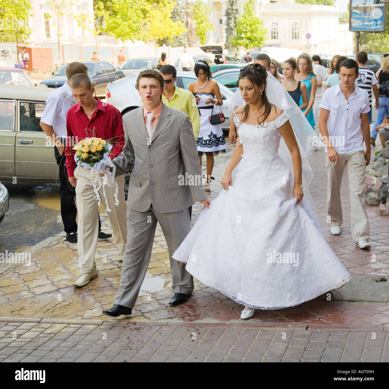 A bridal couple walking through the city together with their wedding guests in Odessa / Ukraine Stock Photo