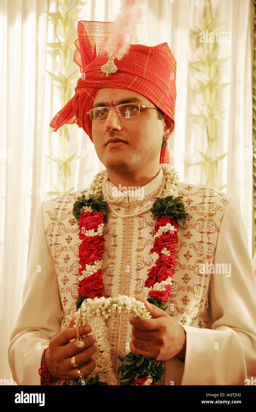 Indian Gujarati Bridegroom wearing turban and embroidered coat Shervani holding garland of flowers for garlanding his bride Stock Photo