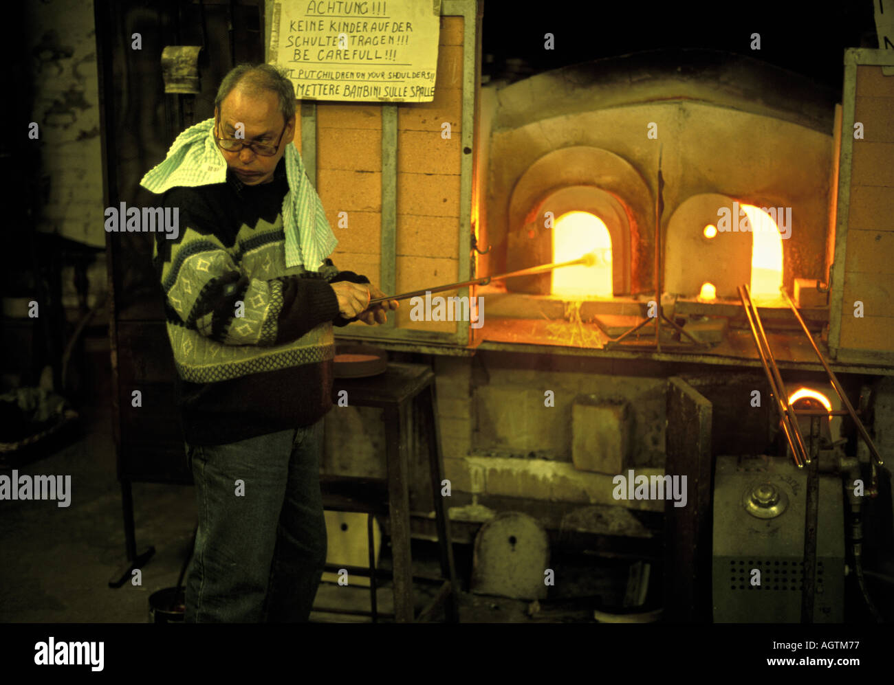 Glass blower at his furnace in Murano glass works Venice Italy Stock
