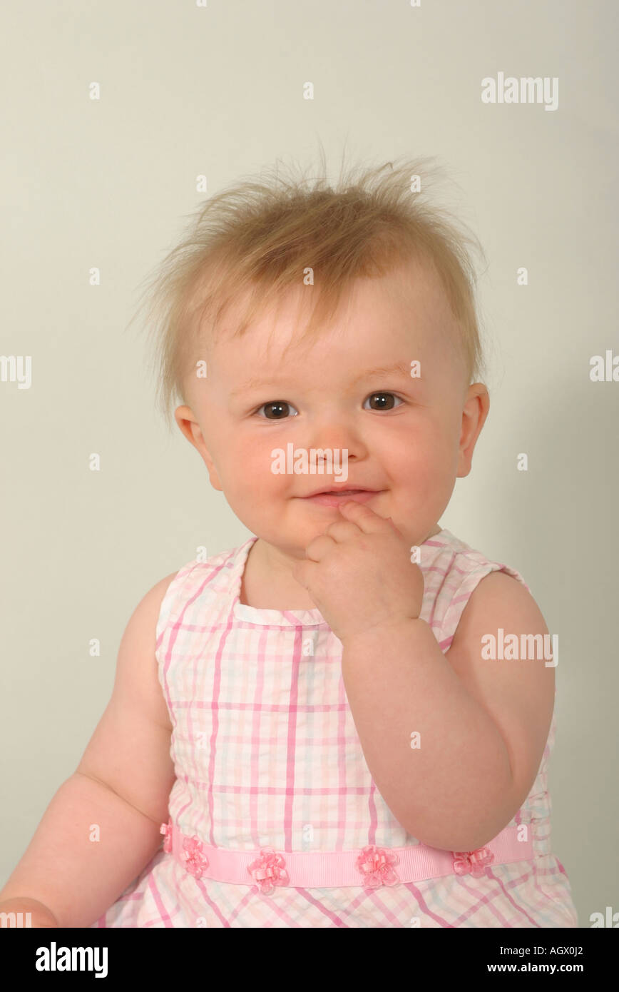 Baby girl with her finger pointing quizzically to her mouth Stock Photo