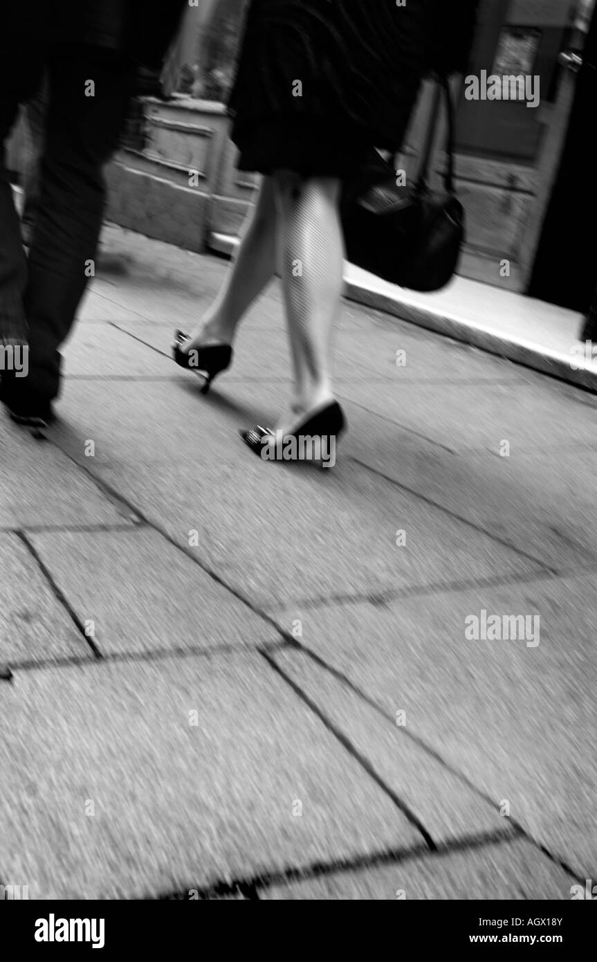 Pavement with man and womans legs walking away from the camera Stock Photo