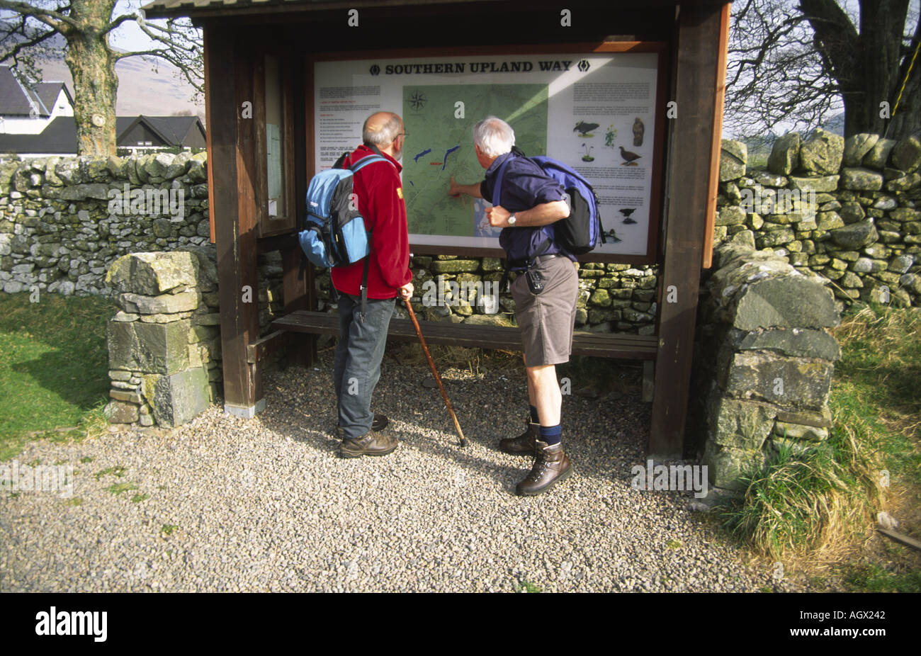 Two walkers on Southern Upland Way St Marys Loch Tibbie Shiels Inn looking at notice board Stock Photo