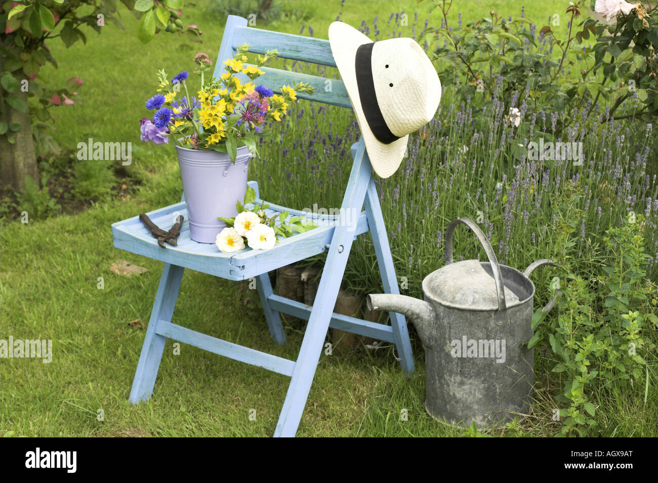 Traditonal english Summer country Garden scene with cut flowers in bucket on garden seat Stock Photo