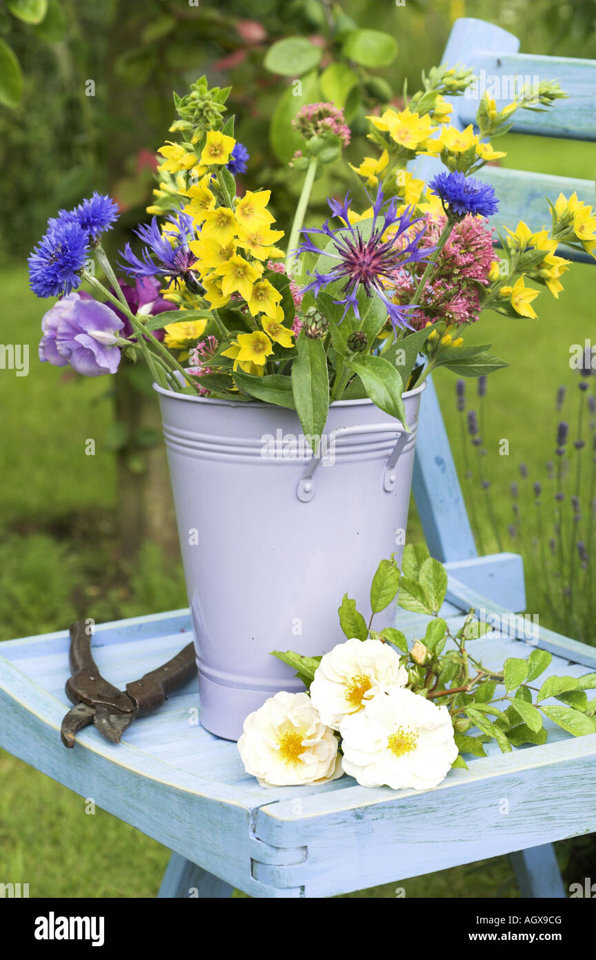 Traditonal english Summer country Garden scene with cut flowers in bucket on garden seat Stock Photo
