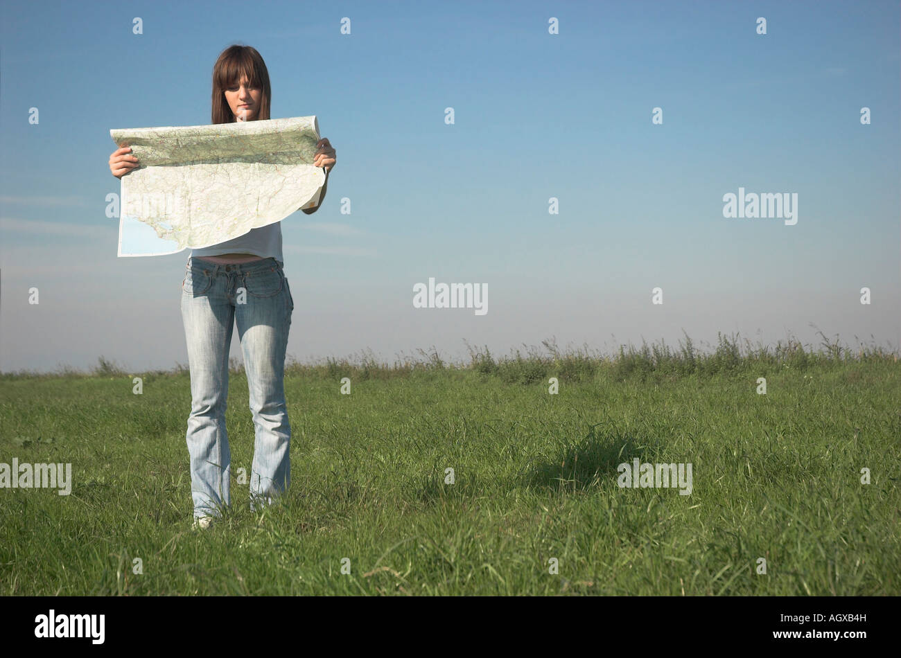Young woman standing in field holding map Stock Photo - Alamy