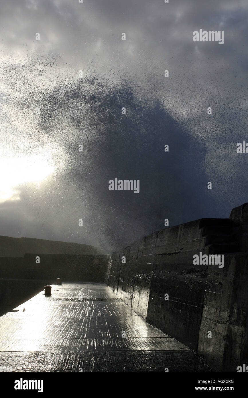 A huge wave crashes over a harbour wall Stock Photo