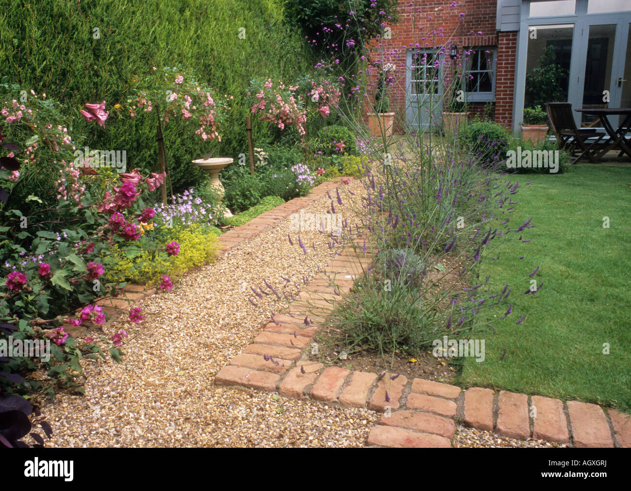 Path gravel brick small back garden design lawn house border flower hedge evergreen Stock Photo