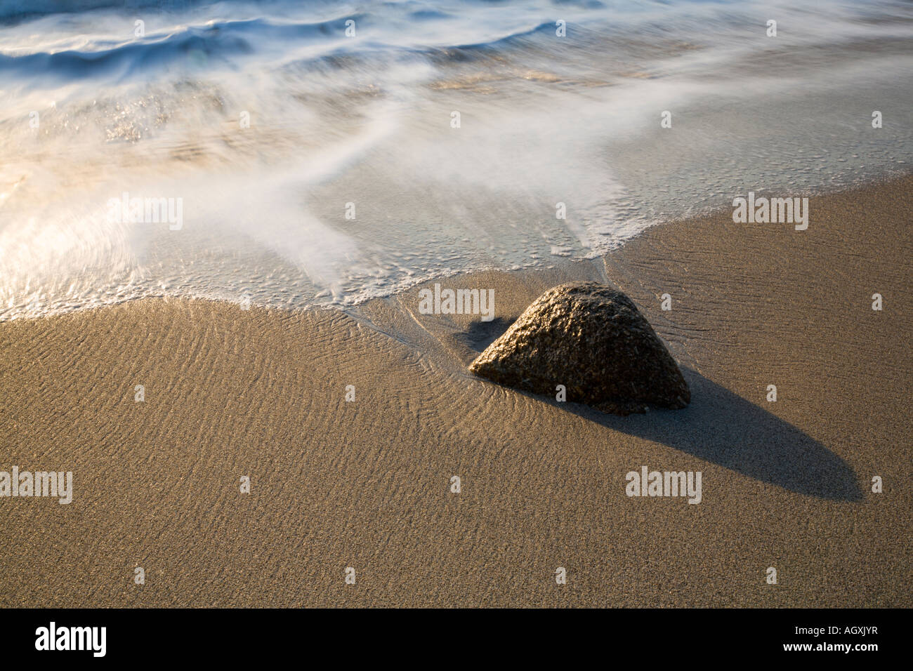 Rock on Gwynver beach at sunset Stock Photo