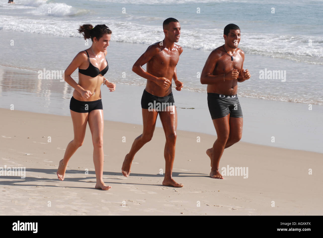 Israel Tel Aviv two young men and a woman jogging on the beach Stock Photo  - Alamy