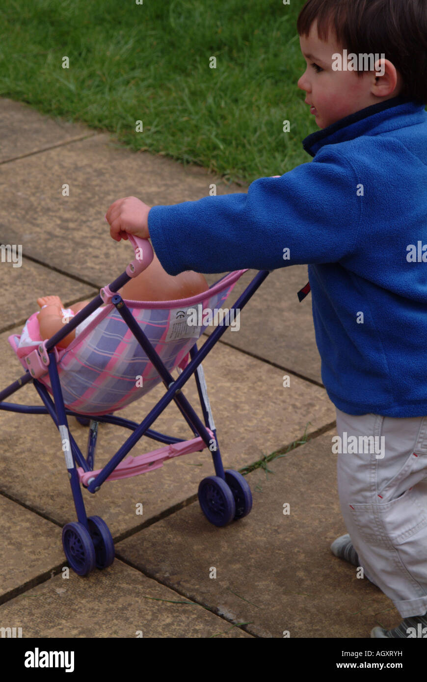 Little boy playing outside with a doll and a pushchair Stock Photo Alamy