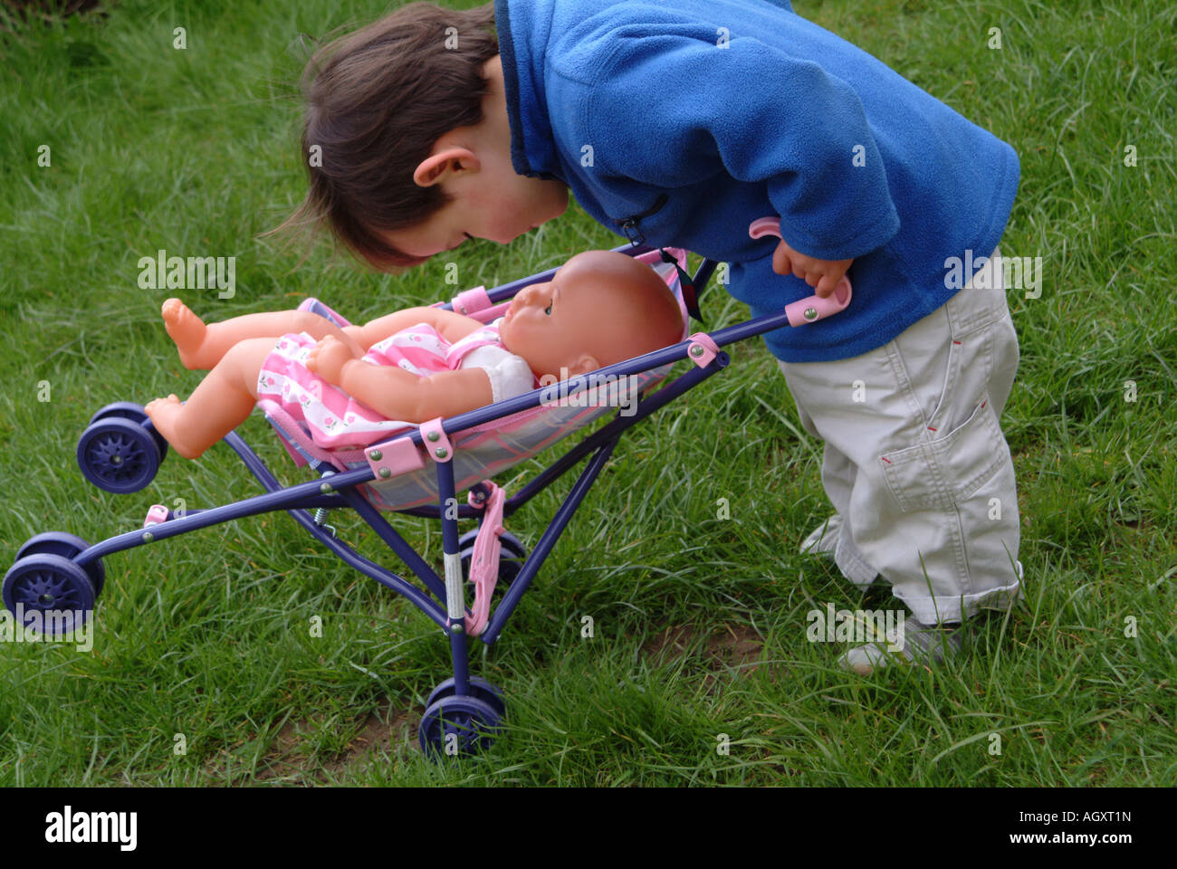 Little boy playing outside with a doll and a pushchair Stock Photo Alamy
