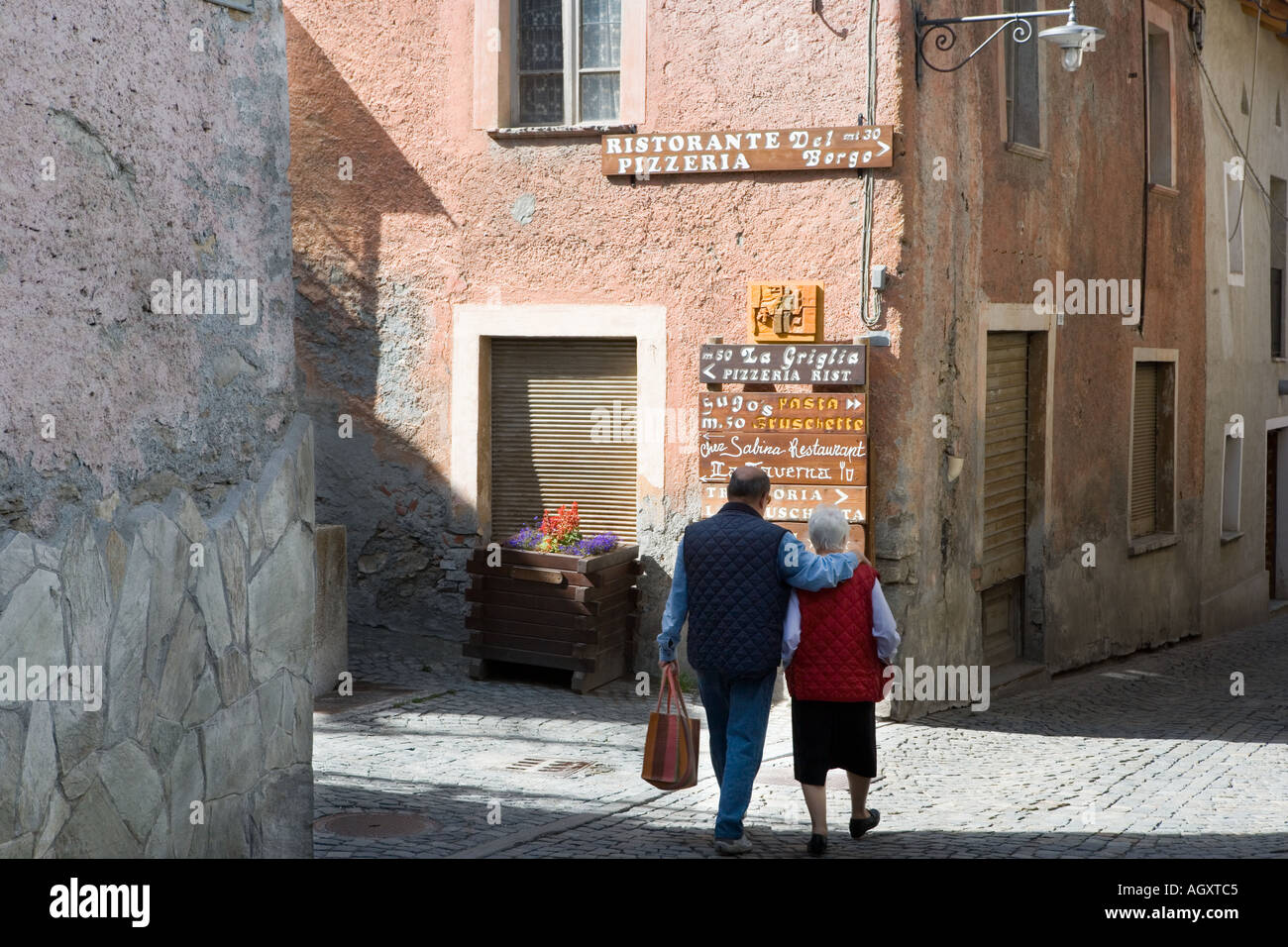 A couple walk through the old town of Sauze d Oulx Piedmonte Italy Stock Photo