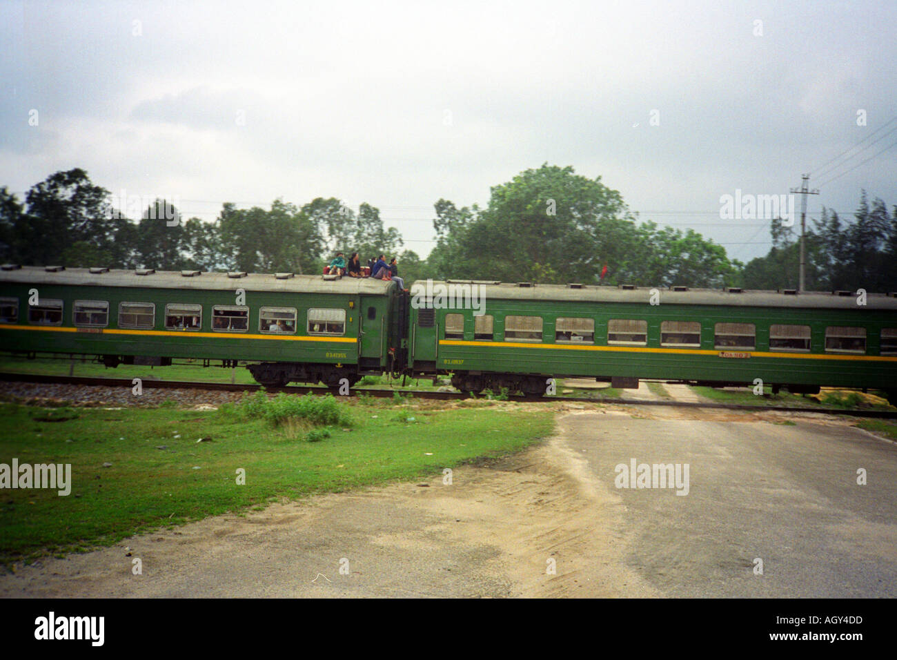 Vietnam Near Hoi An level crossing train passengers riding on roof free ride Reunification Express Stock Photo