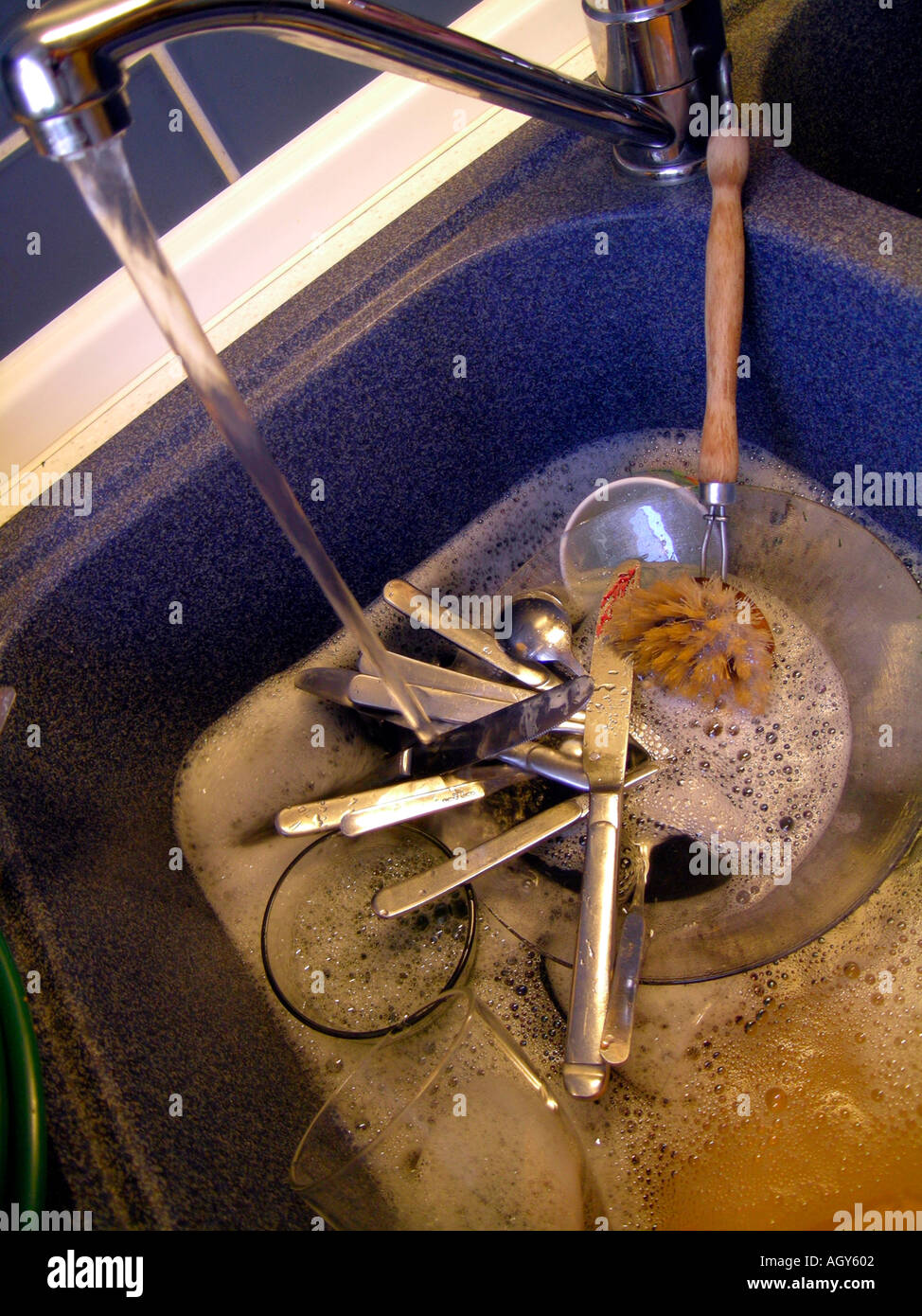 dirty crockery in water in a sink waiting for somebody to do the dishes Stock Photo