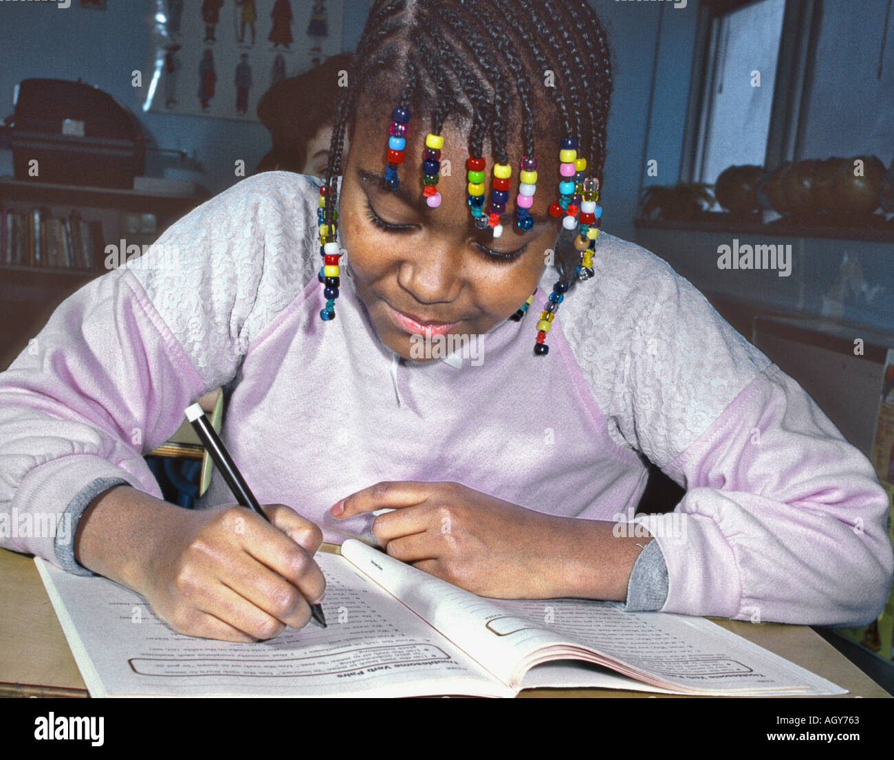 Black female middle school student works at desk with workbook Stock Photo