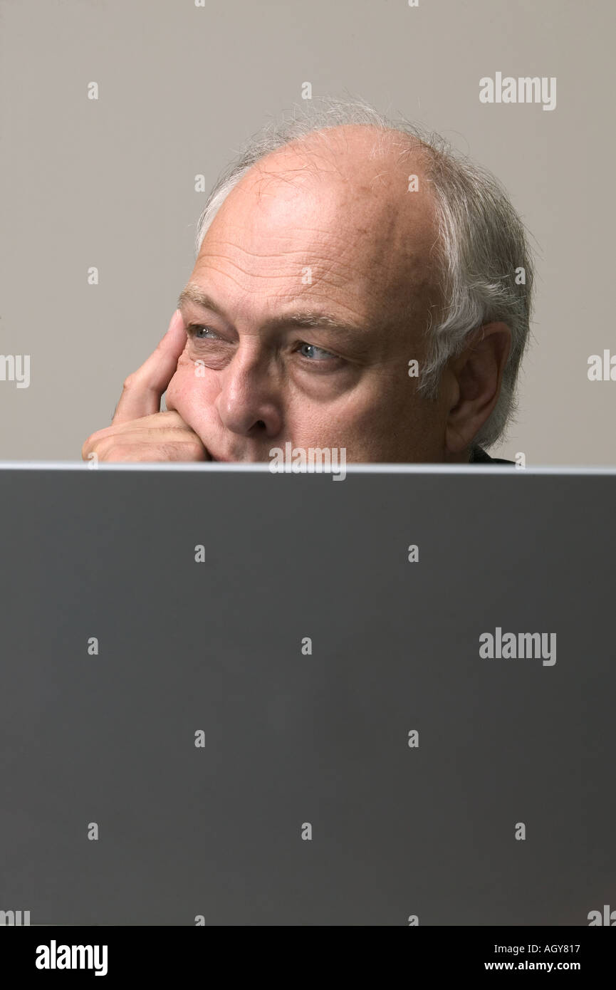 Ageing Corporate executive reviews information on portable computer in office building Stock Photo