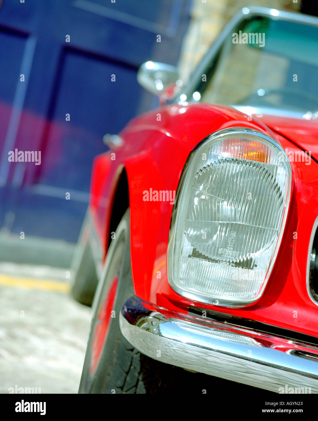detail of red mercedes car parked outside an expensive urban mews property with navy blue doors Stock Photo
