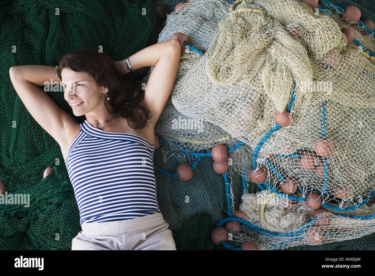 https://c8.alamy.com/comp/AH00JW/high-angle-view-of-a-mid-adult-woman-lying-on-commercial-fishing-nets-AH00JW.jpg