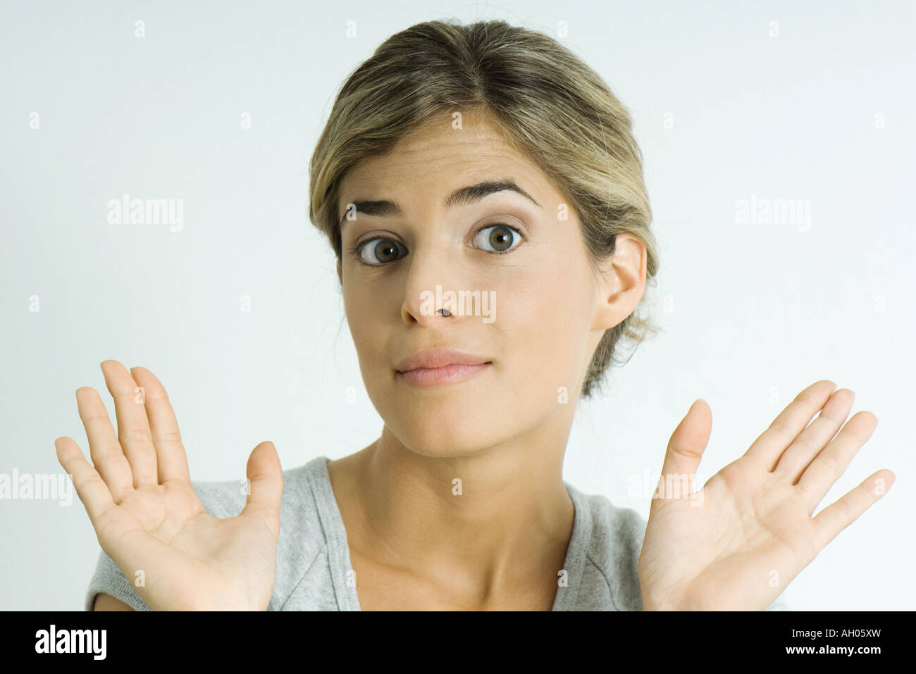 Young woman raising eyebrows, holding up palms, portrait Stock Photo
