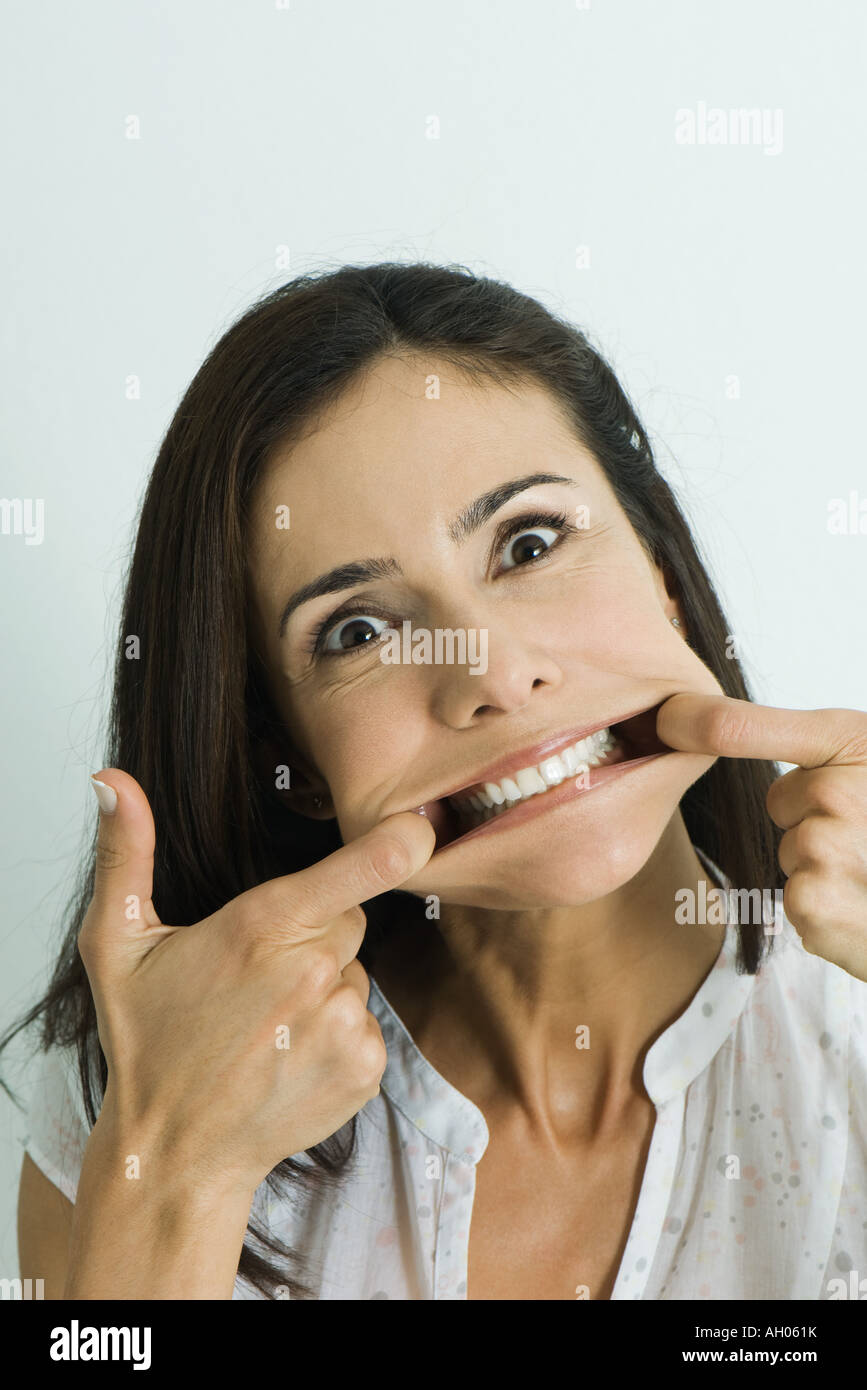 Woman pulling sides of mouth, looking at camera, portrait Stock Photo