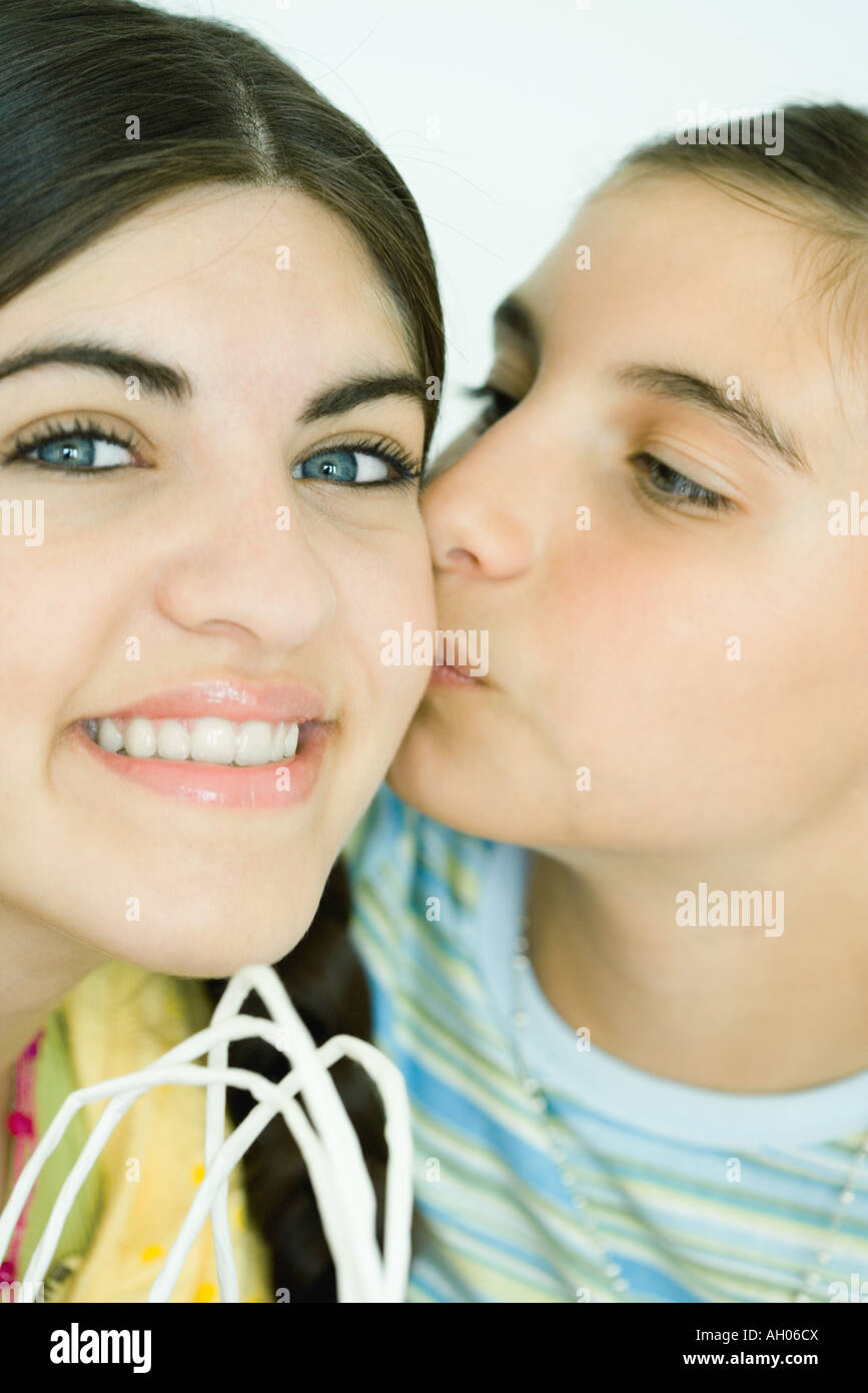 Two young female friends, one kissing the other on the cheek Stock Photo
