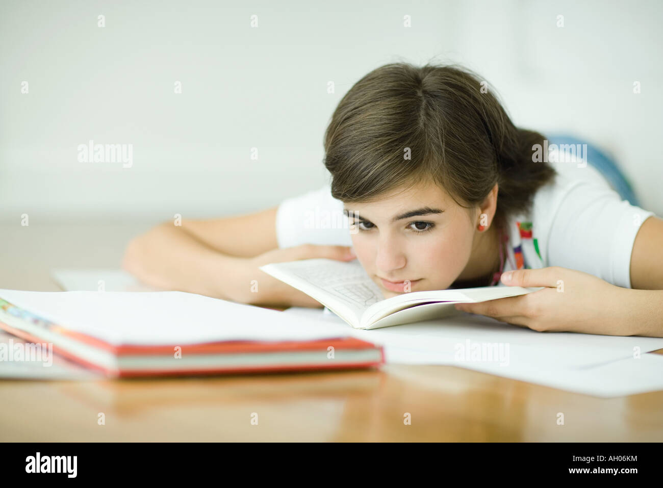 Teen girl lying on floor, doing homework Stock Photo