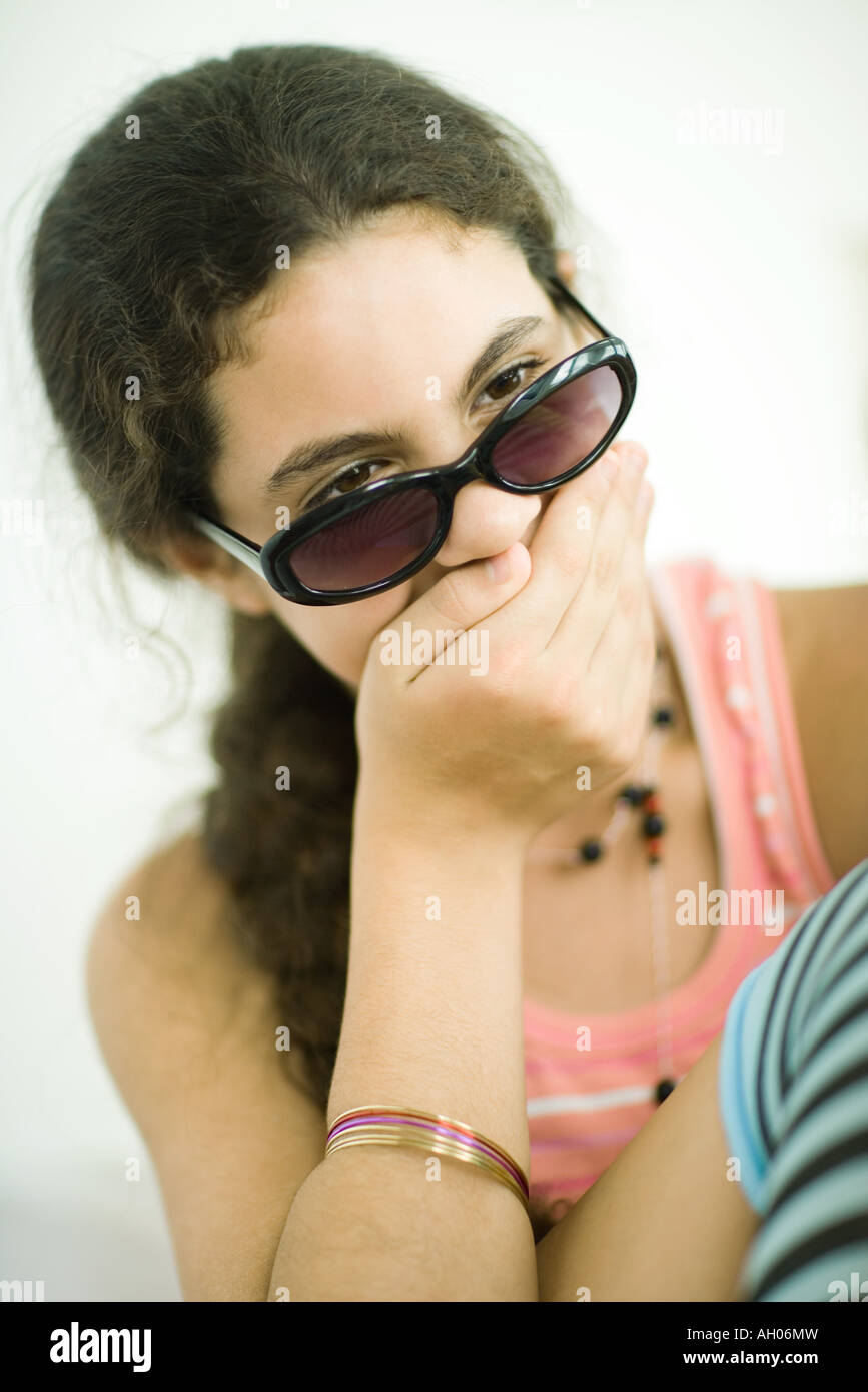 Preteen girl holding hand over mouth, looking over sunglasses, portrait Stock Photo