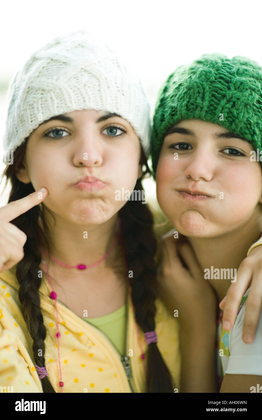 Young female friends wearing knit hats, puffing out cheeks Stock Photo