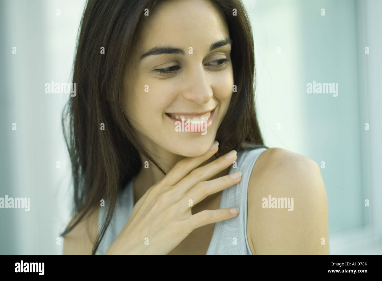 Young woman, looking away, hand under chin, head and shoulders