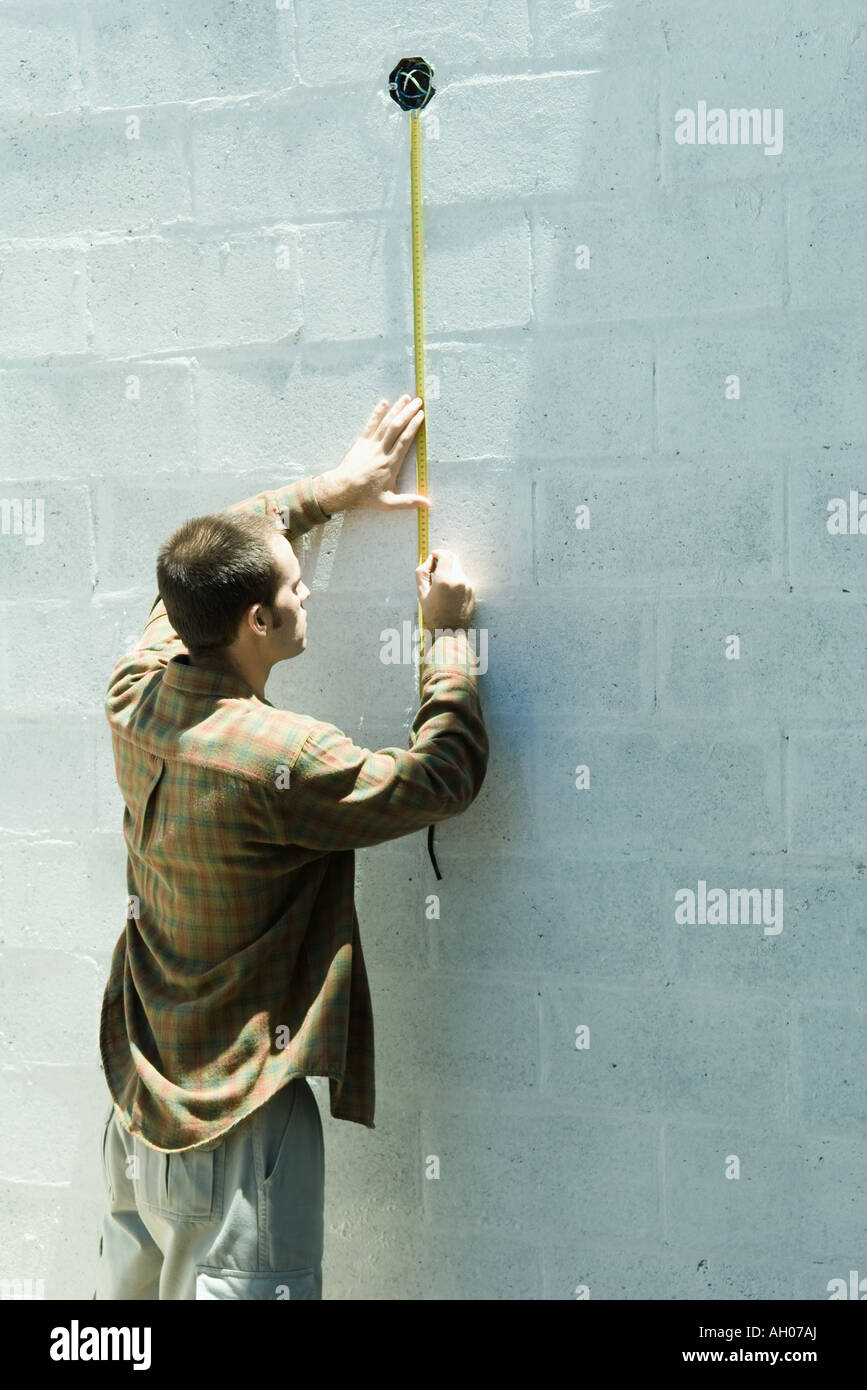 Man using measuring tape on cinder block wall Stock Photo Alamy