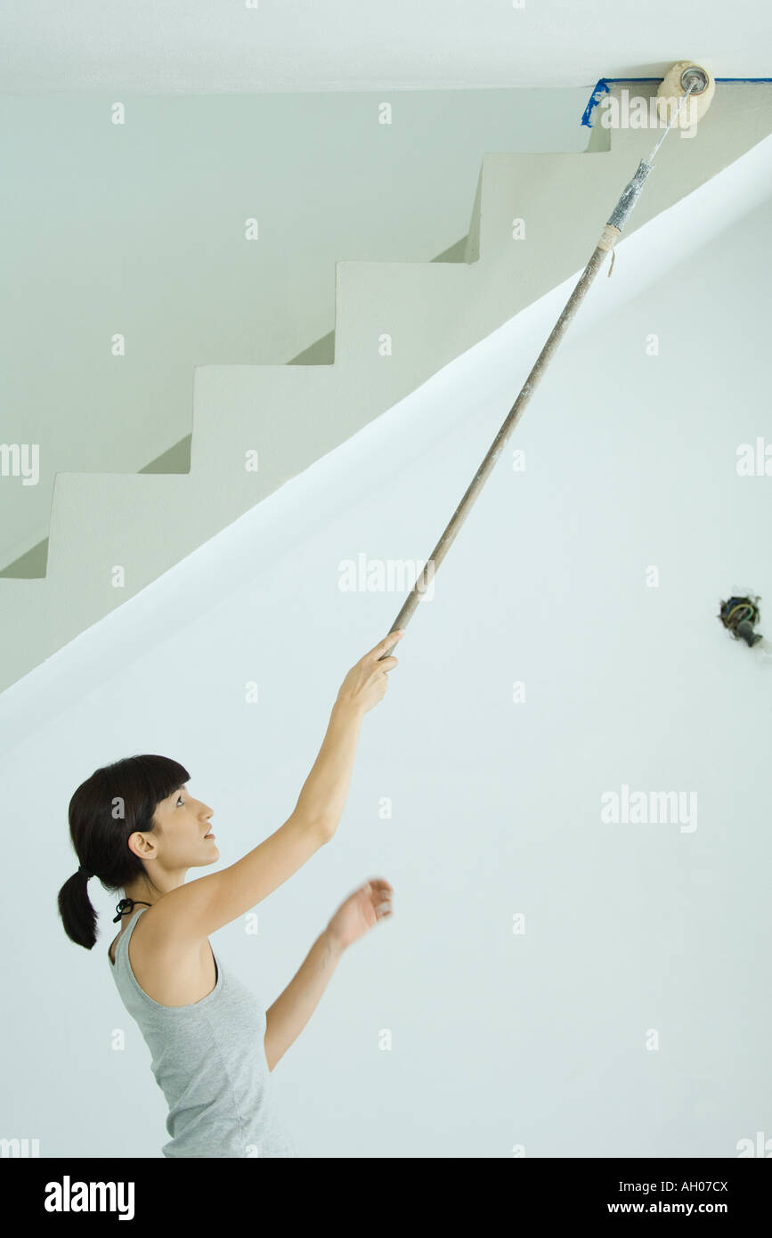 Woman Painting Ceiling With Roller Extension Stock Photo