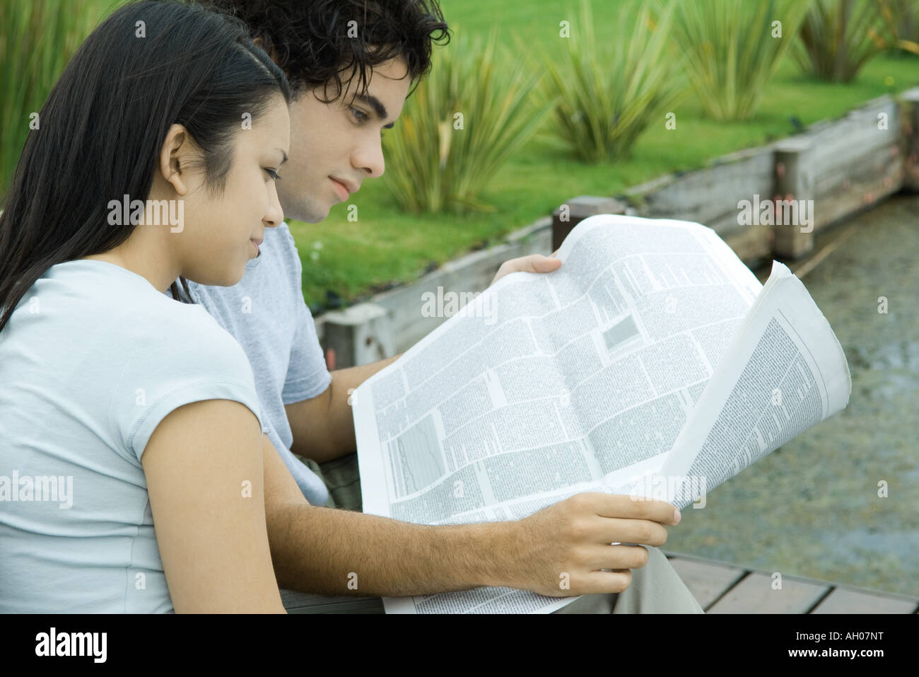Young couple reading newspaper together outdoors Stock Photo