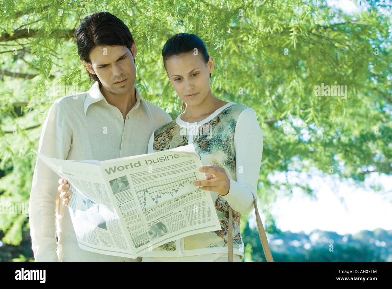 Couple standing outdoors, reading newspaper Stock Photo