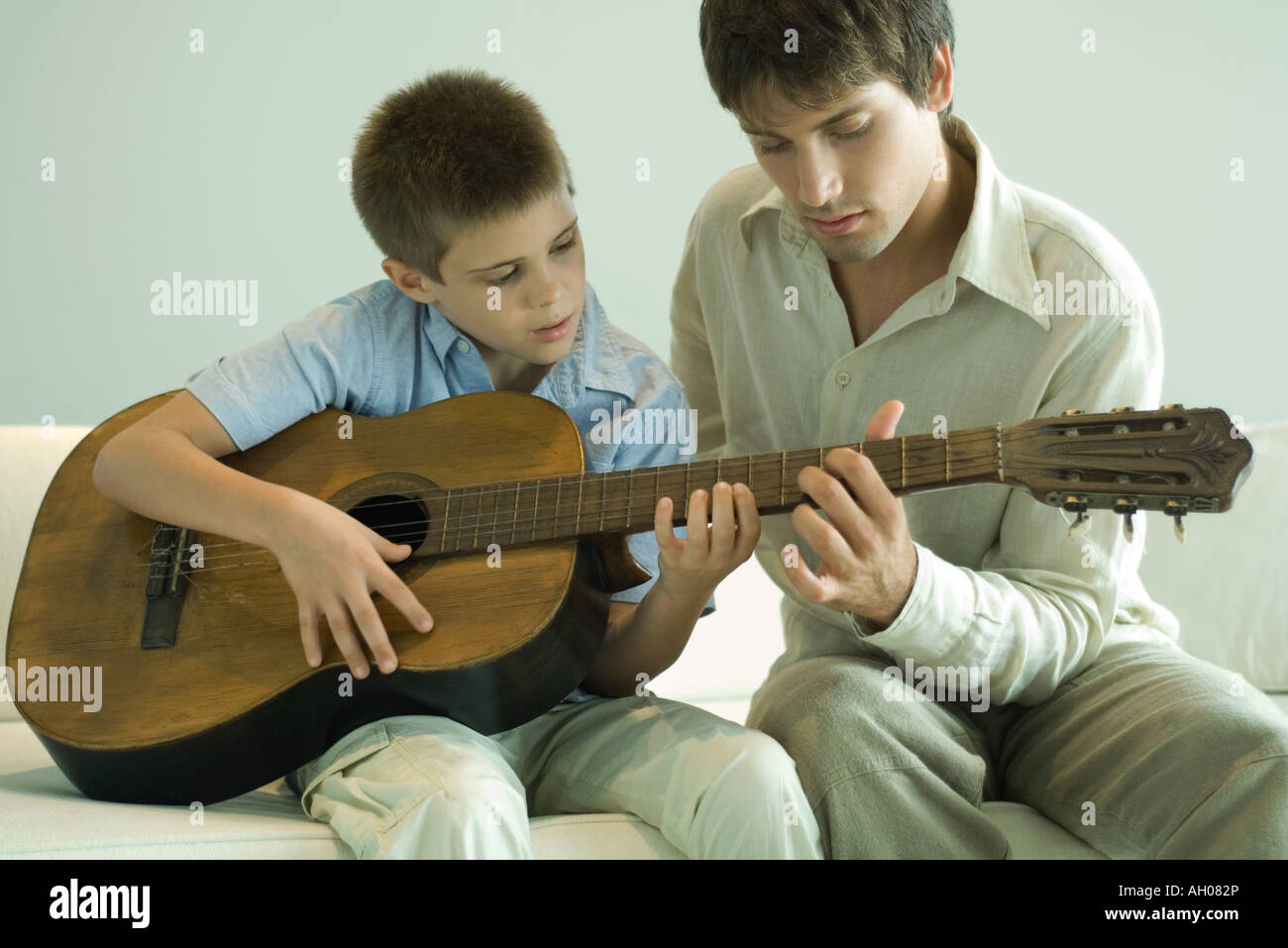 Man teaching boy to play the guitar Stock Photo