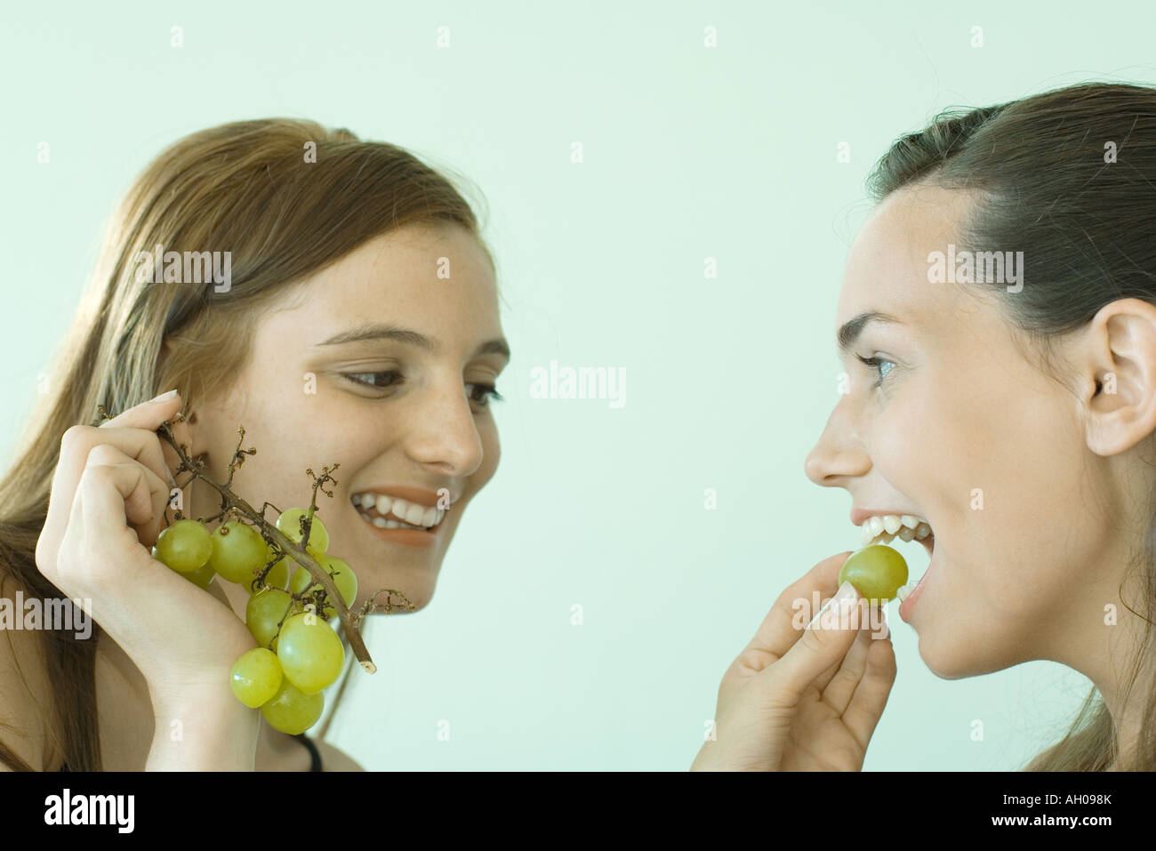 Young woman feeding her friend grapes, both smiling Stock Photo Alamy